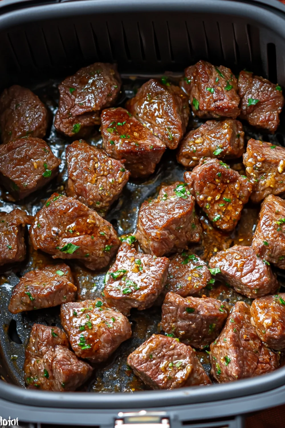 Tender chunks of steak cooked to perfection in the air fryer with a rich garlic butter glaze, garnished with fresh parsley, creating a savory and mouth-watering dish.