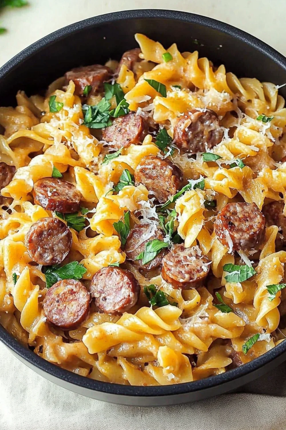 A flavorful one-pot smoked sausage pasta with rotini noodles, sliced sausage, and a creamy sauce, topped with fresh herbs and parmesan cheese.